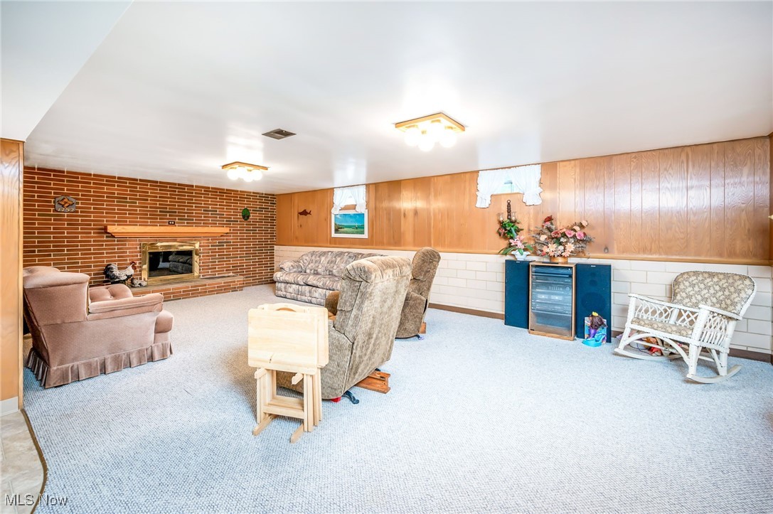 126 South Rhodes Avenue Niles, OH 44446 - Photo 19 of 23 Carpeted living room featuring a brick fireplace, wine cooler, wood walls, and brick wall
