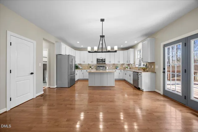 a large living room with stainless steel appliances granite countertop a couch and a wooden floor