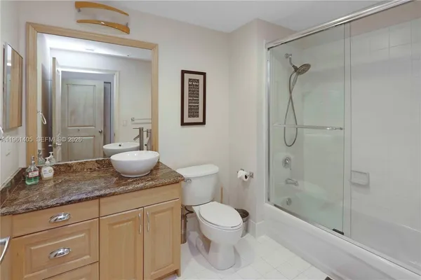 a bathroom with a granite countertop sink toilet a mirror and shower