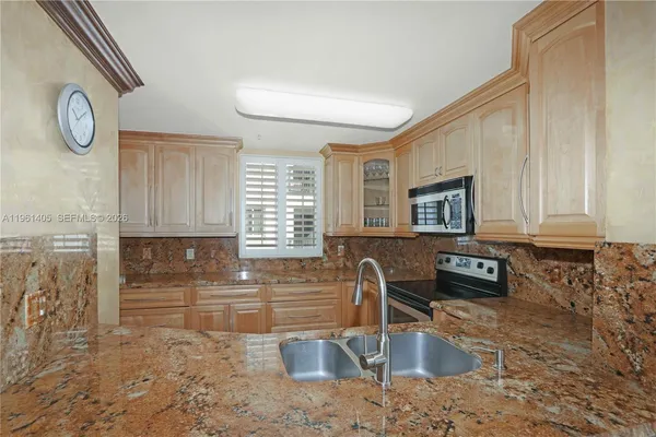 a kitchen with granite countertop a sink a stove and cabinets