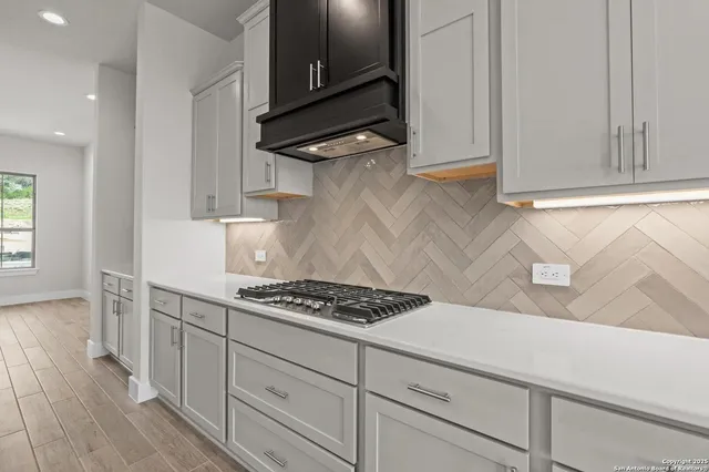 a kitchen with white cabinets and a stove top oven
