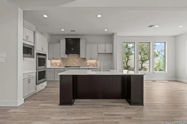a kitchen with granite countertop a stove a sink and a refrigerator