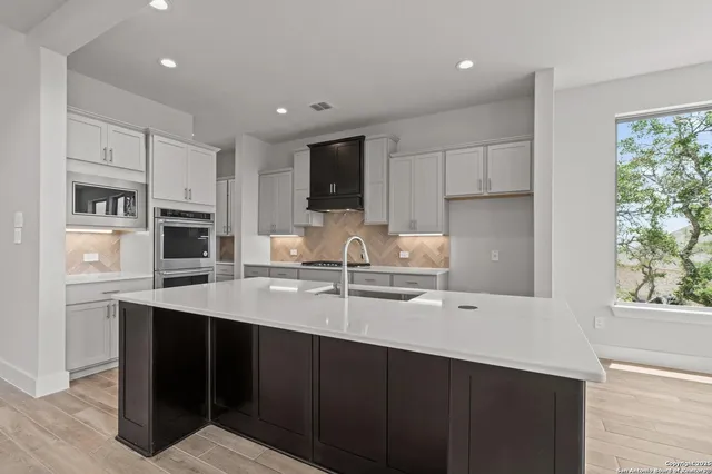 a kitchen with stainless steel appliances granite countertop a sink a stove a microwave a sink a refrigerator and cabinets