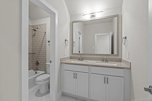 a bathroom with a granite countertop toilet a sink and a mirror