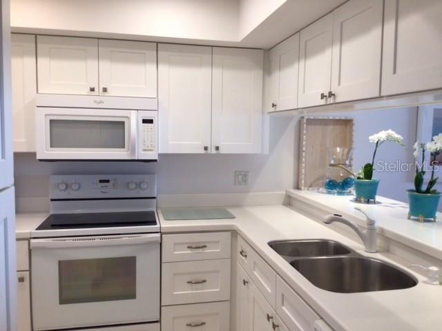 420 Gulf Boulevard, Unit 6 Boca Grande, FL 33921 - Photo 11 of 26 a kitchen with granite countertop white cabinets and white appliances