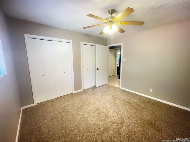 an empty room with a chandelier fan and closet