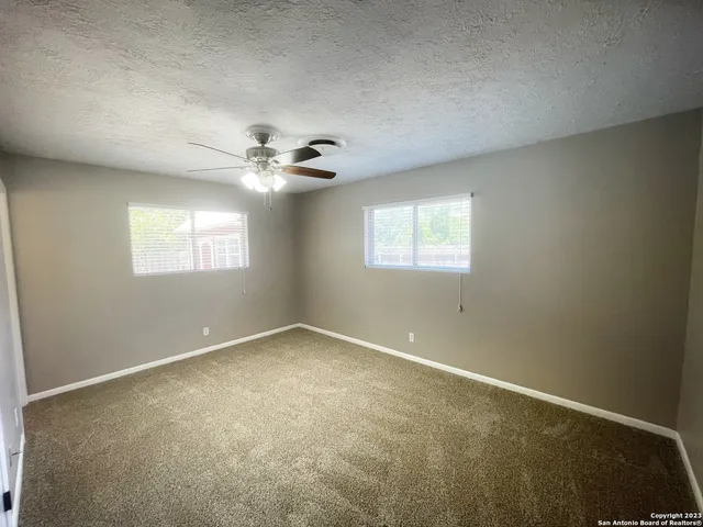an empty room with windows and chandelier fan
