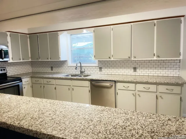 a kitchen with a sink stove and white cabinets with wooden floor