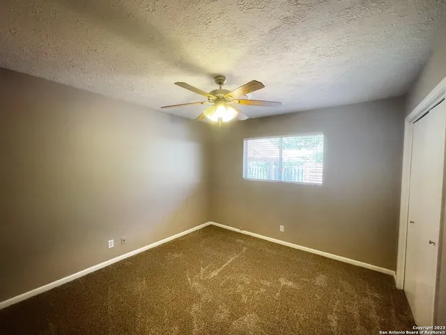 an empty room with a window and a ceiling fan