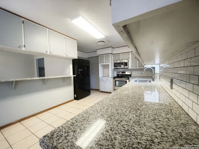 a kitchen with granite countertop a refrigerator and a sink
