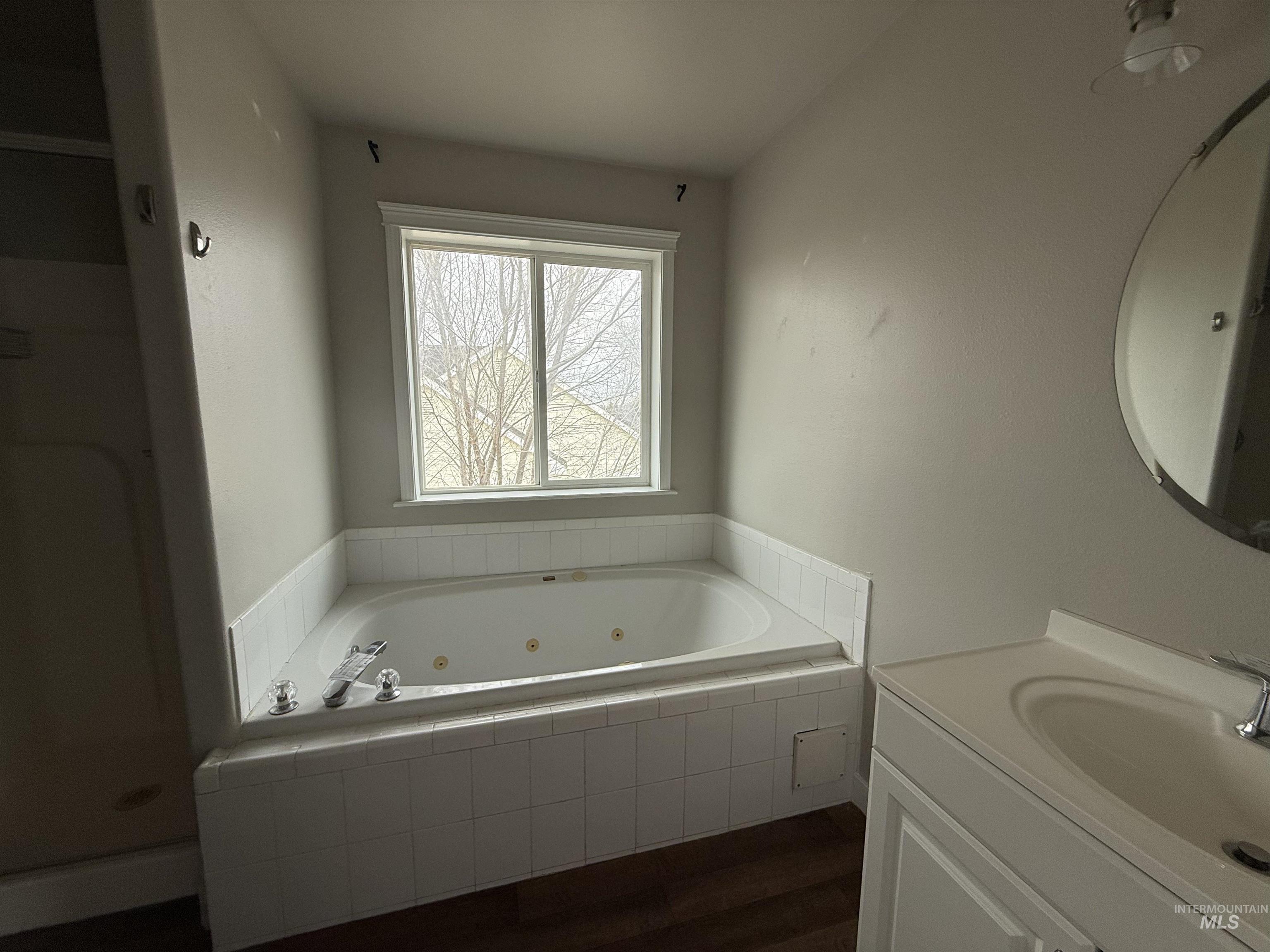 538 Morning Sun Drive Nampa, ID 83686 - Photo 18 of 28 Bathroom featuring a tub with jets, dark wood-type flooring, and vanity