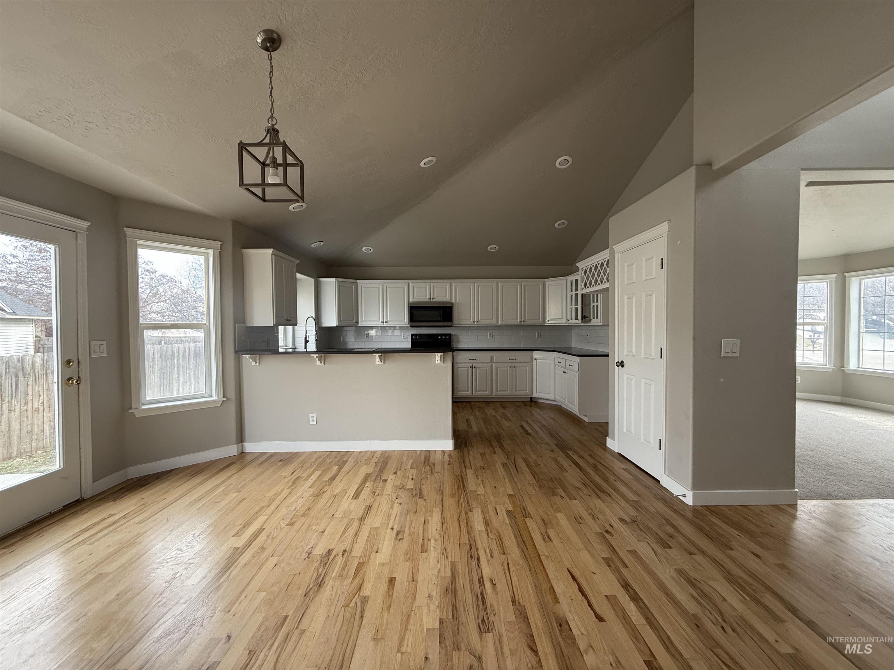 538 Morning Sun Drive Nampa, ID 83686 - Photo 7 of 28 Kitchen featuring dark countertops, white cabinets, a peninsula, light wood-style floors, and vaulted ceiling