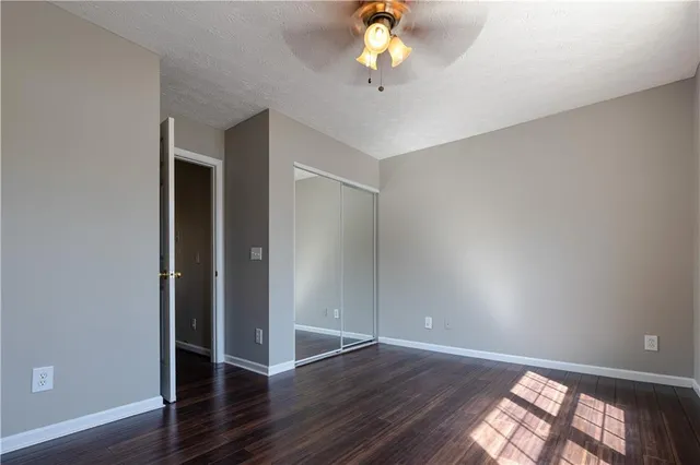 an empty room with wooden floor chandelier fan and windows