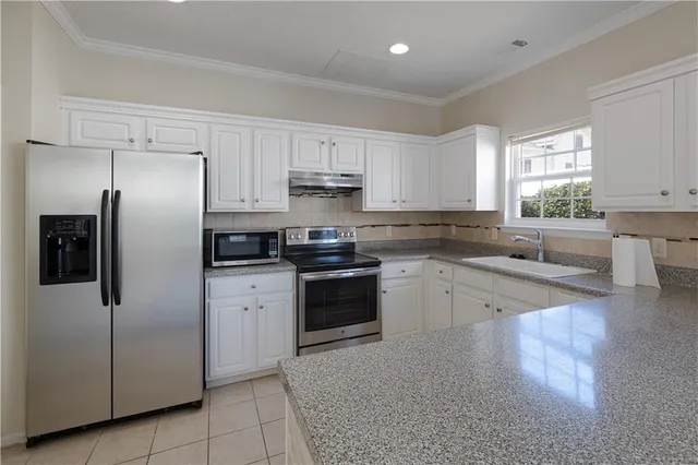 a kitchen with granite countertop white cabinets and stainless steel appliances