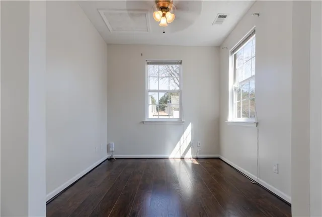 a view of an empty room with wooden floor fireplace and a window