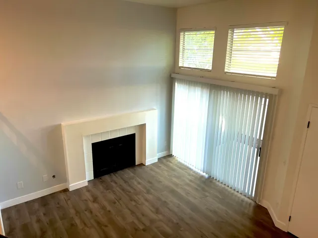 an empty room with windows and fireplace