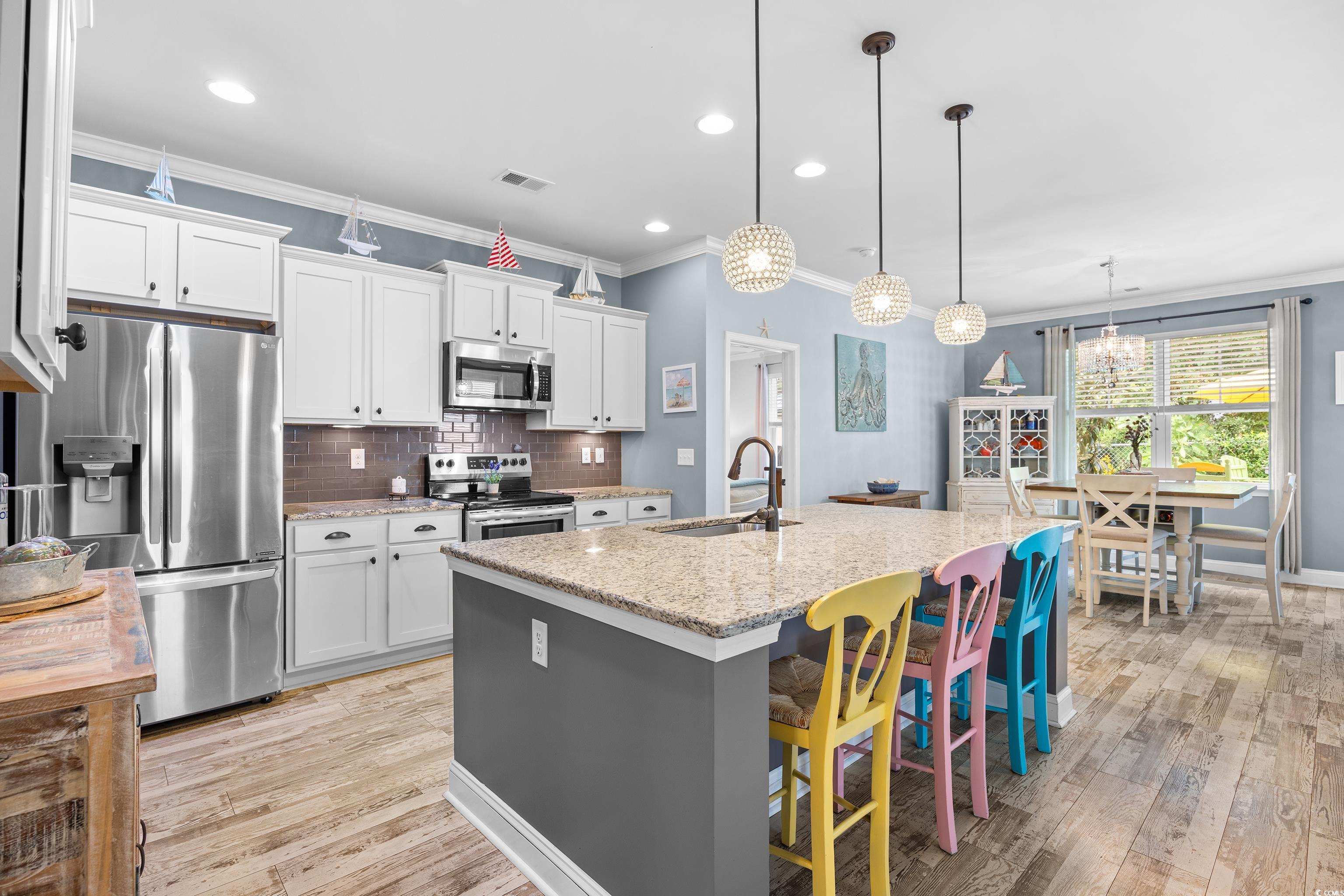 1104 Inlet View Drive North Myrtle Beach, SC 29582 - Photo 20 of 40 Kitchen with ornamental molding, stainless steel appliances, decorative backsplash, light wood-style flooring, and white cabinets