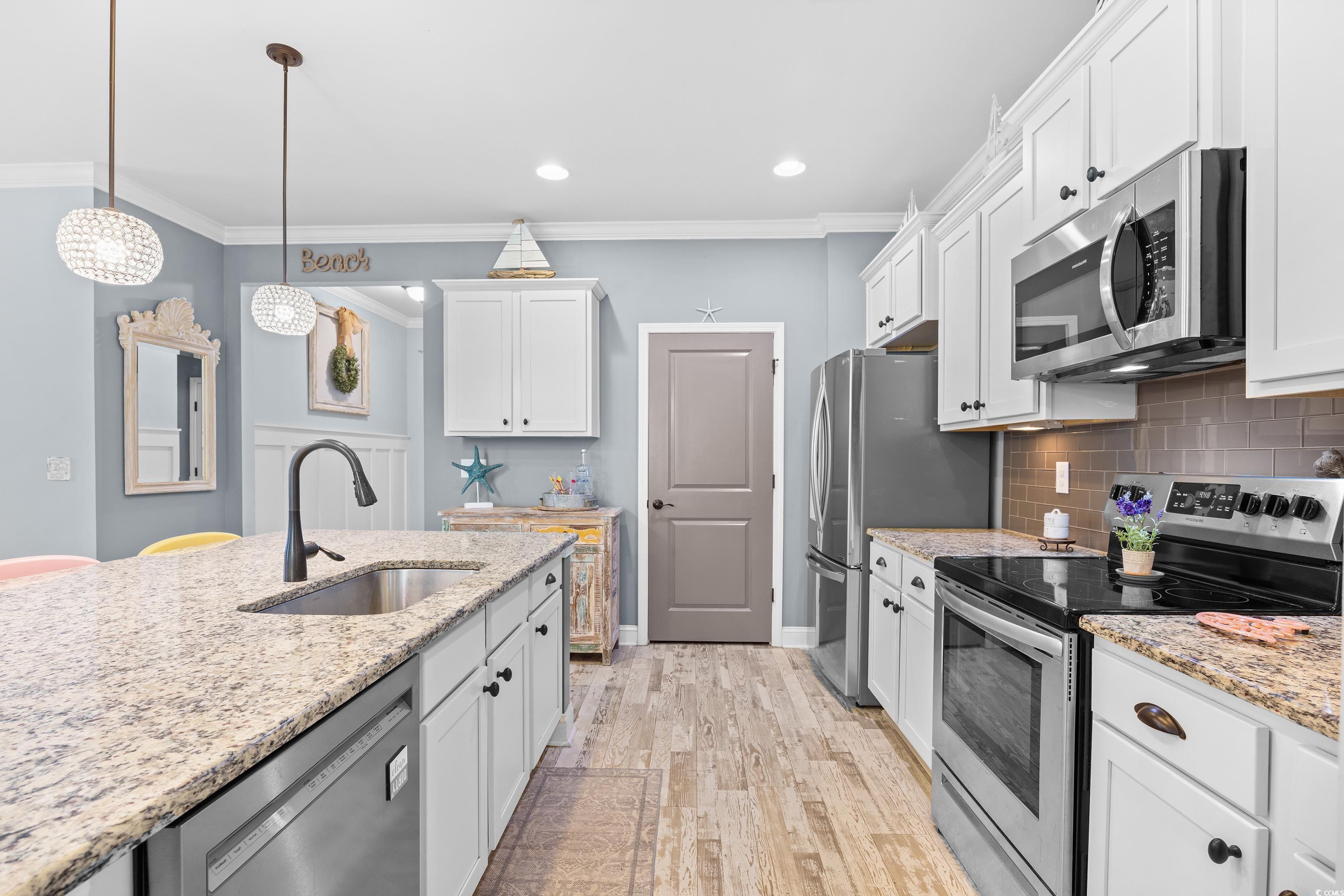 1104 Inlet View Drive North Myrtle Beach, SC 29582 - Photo 23 of 40 Kitchen with appliances with stainless steel finishes, backsplash, ornamental molding, white cabinets, and light wood-style flooring
