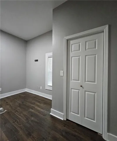 an empty room with wooden floor & closet area