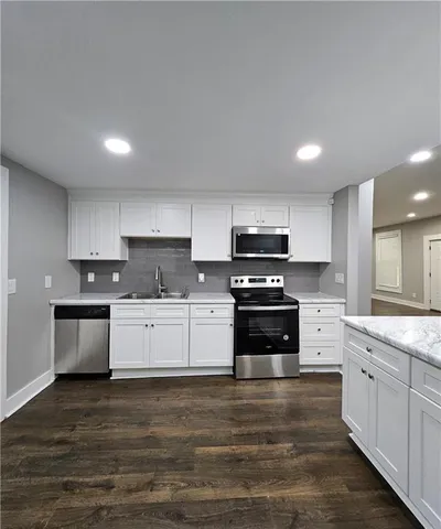 a kitchen with granite countertop white cabinets and stainless steel appliances