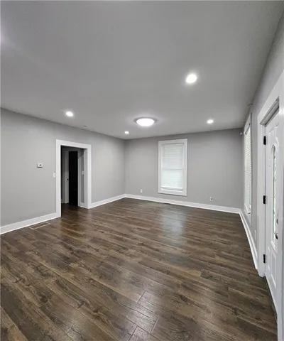 a view of an empty room with wooden floor and closet