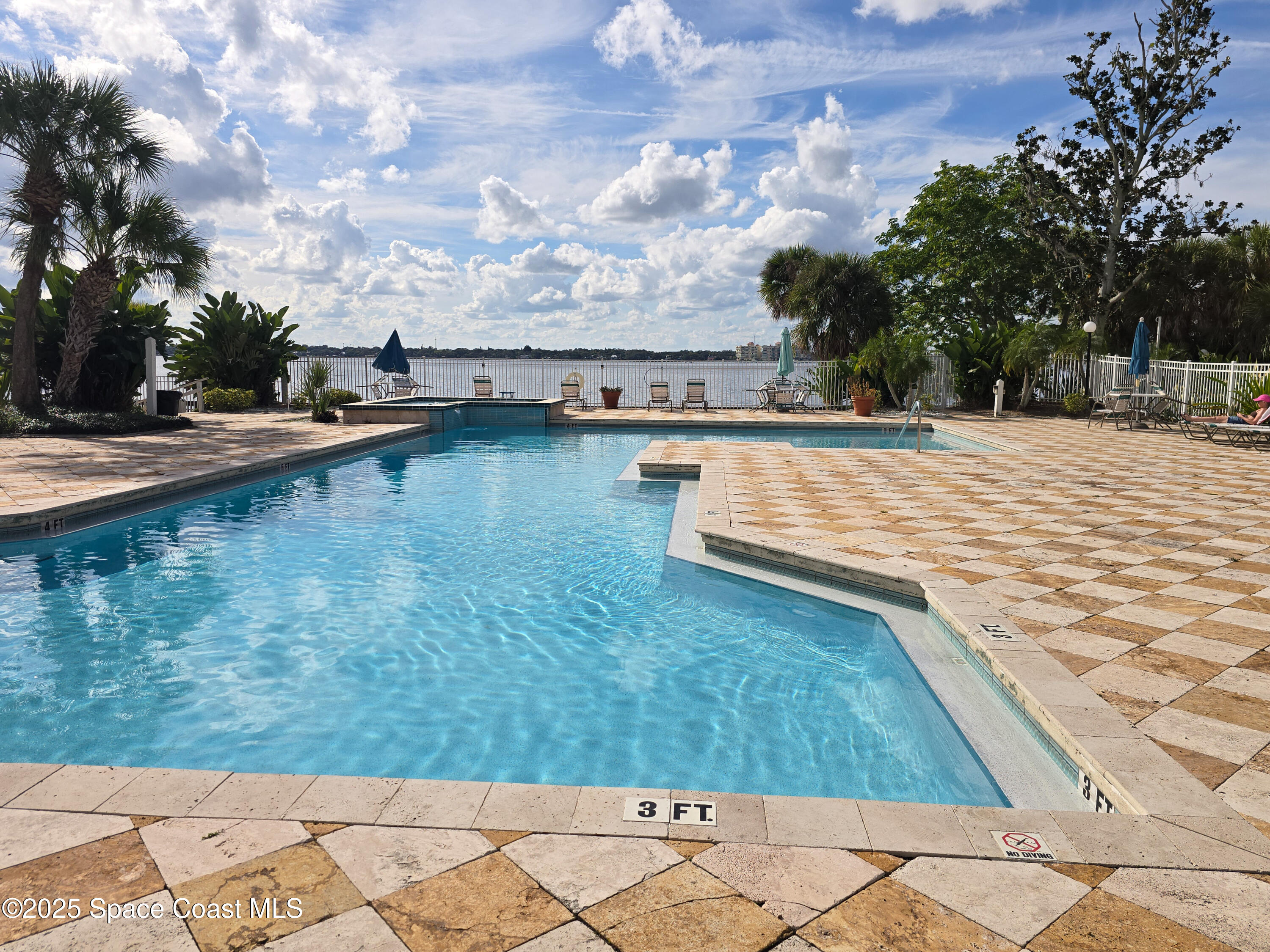 225 South Tropical Trail, Unit 217 Merritt Island, FL 32952 - Photo 12 of 18 a view of swimming pool with outdoor seating and trees in the background