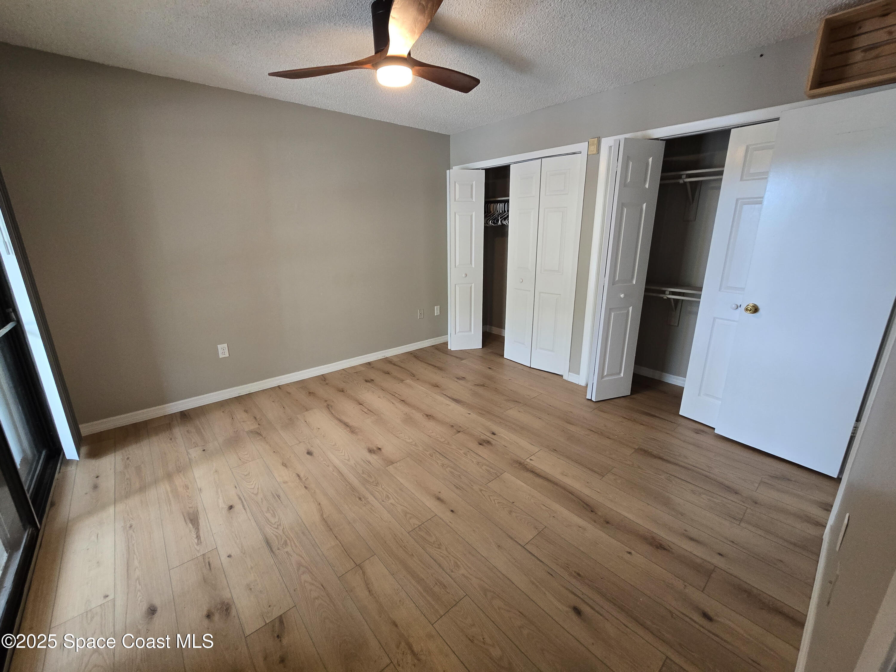 225 South Tropical Trail, Unit 217 Merritt Island, FL 32952 - Photo 6 of 18 an empty room with wooden floor fan and windows
