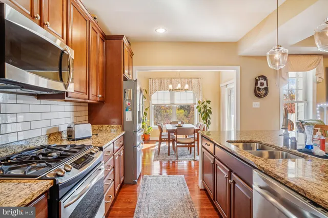a kitchen with stainless steel appliances granite countertop a stove a sink and a microwave