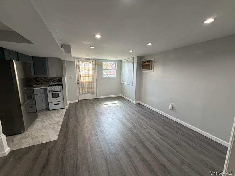 179-11 Eveleth Road Queens, NY 11434 - Photo 3 of 6 an empty room with wooden floor electric appliances and windows