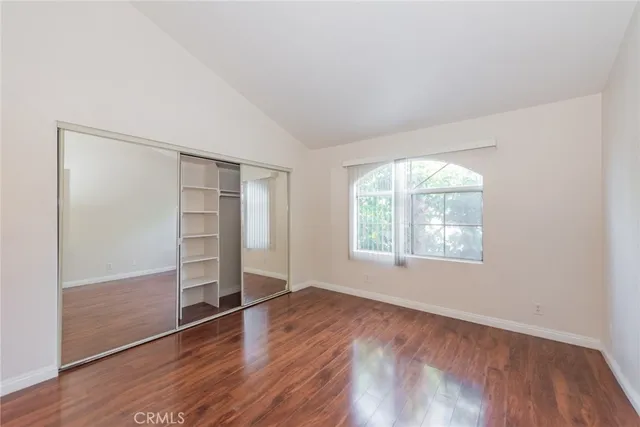 an empty room with wooden floor closet and windows