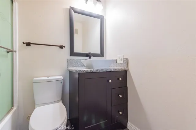 a bathroom with a granite countertop toilet sink and mirror