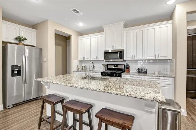 a kitchen with stainless steel appliances granite countertop a stove top oven a refrigerator a sink and dishwasher