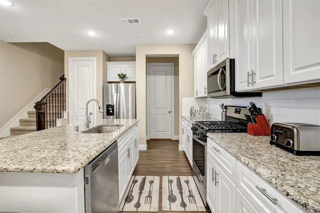 a kitchen with granite countertop stainless steel appliances and white cabinets