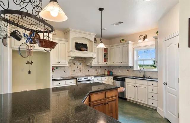 a kitchen with stainless steel appliances granite countertop a sink a stove and a refrigerator