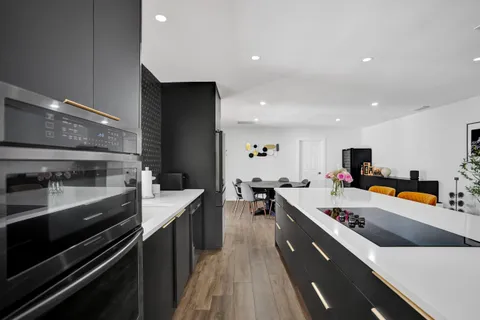 a large kitchen with a large counter top a sink stainless steel appliances and cabinets