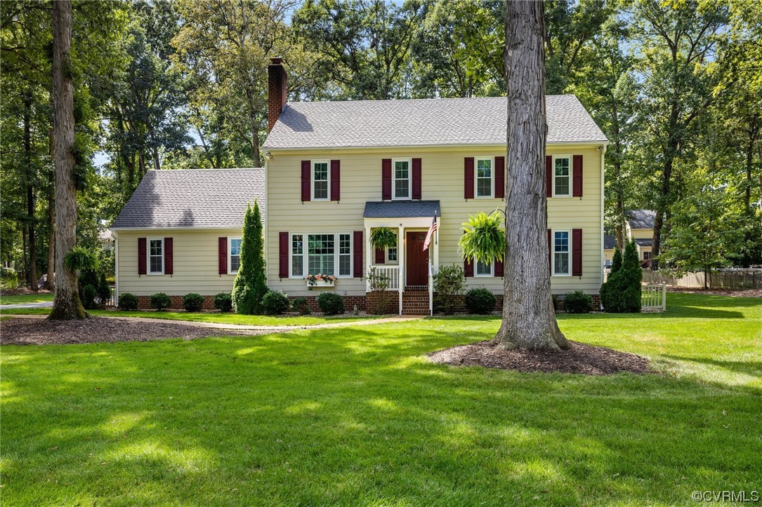 a front view of a house with a garden and trees