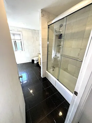 a bathroom with a glass shower door and a window