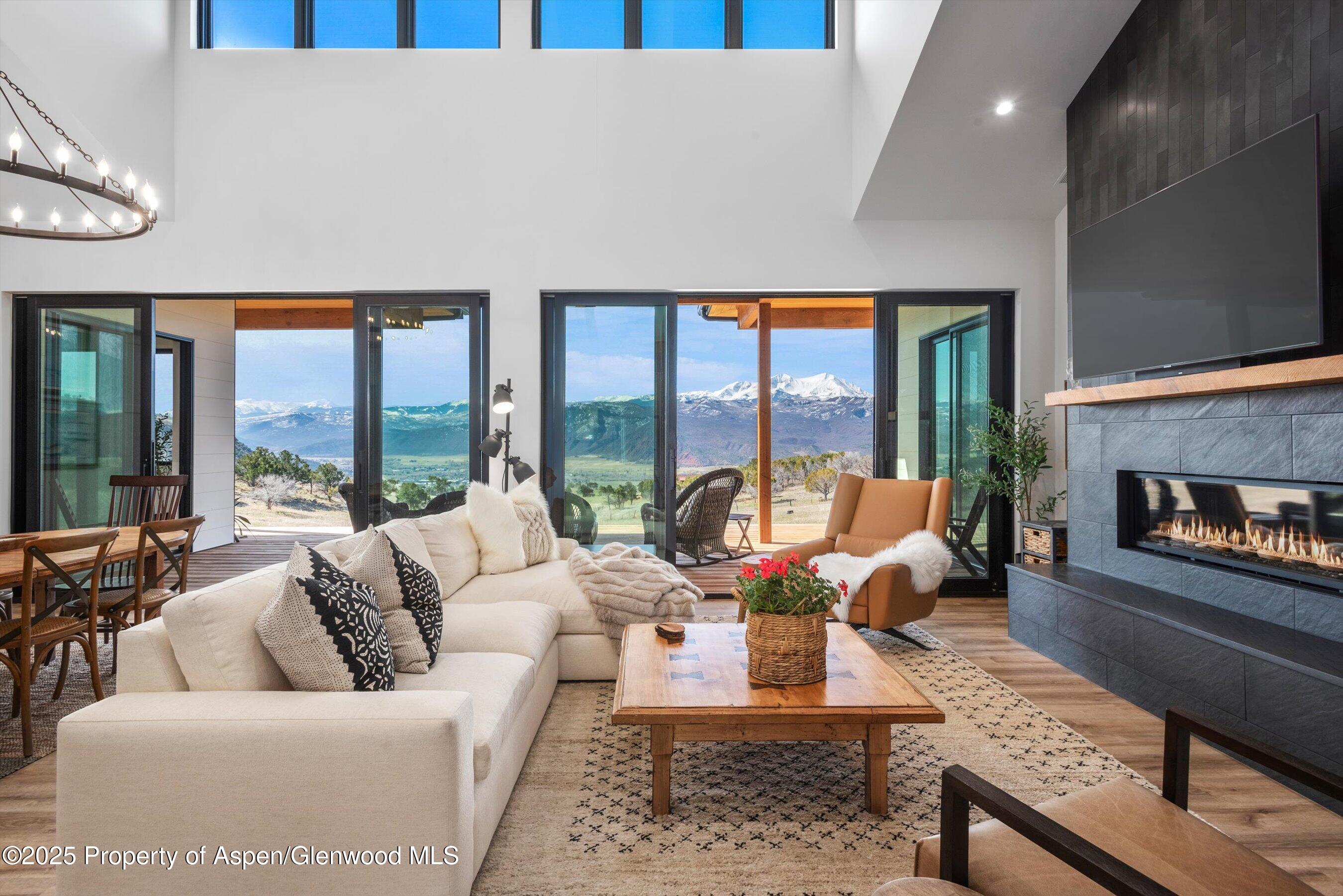 a living room with furniture large windows and a fireplace