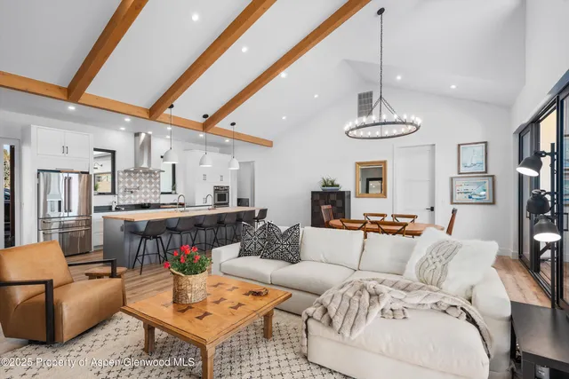a living room with furniture kitchen view and a chandelier
