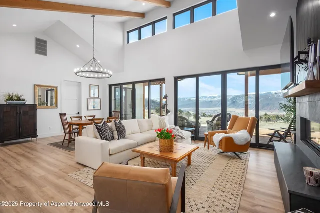 a living room with furniture large windows and wooden floor