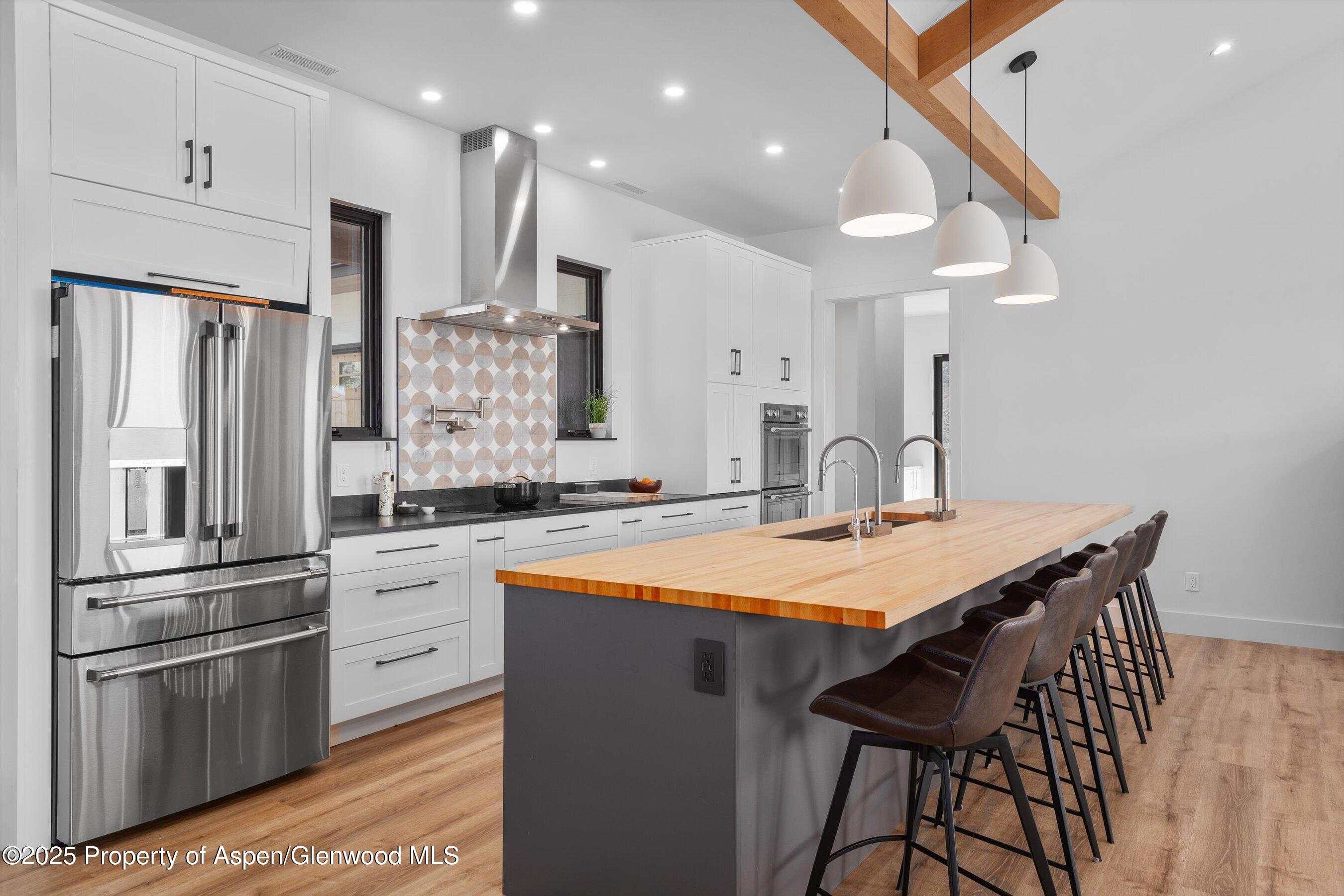 1840 Upper Cattle Creek Road Carbondale, CO 81623 - Photo 7 of 37 a kitchen with stainless steel appliances kitchen island granite countertop a table chairs in it and wooden floors