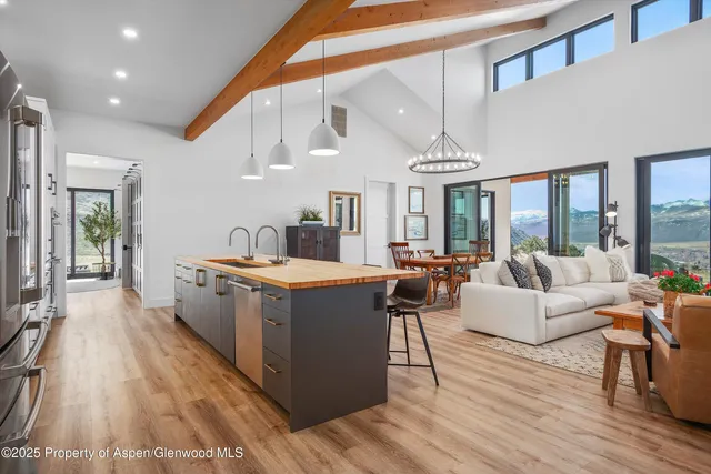 a large living room with stainless steel appliances granite countertop wooden floor a couch and a chandelier