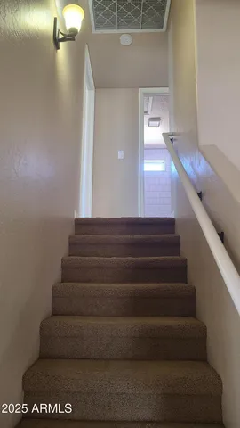 an empty room with wooden floor and a kitchen