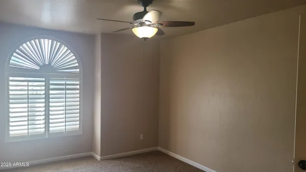 an empty room with closet and a chandelier fan