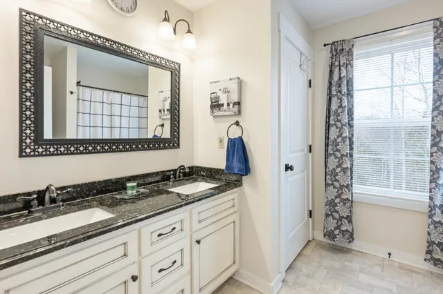 a bathroom with a granite countertop sink a mirror and a shower