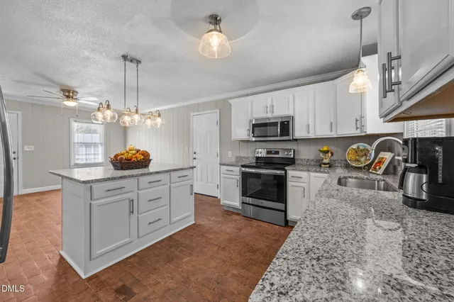 a kitchen with granite countertop stainless steel appliances cabinets a sink and a counter top space