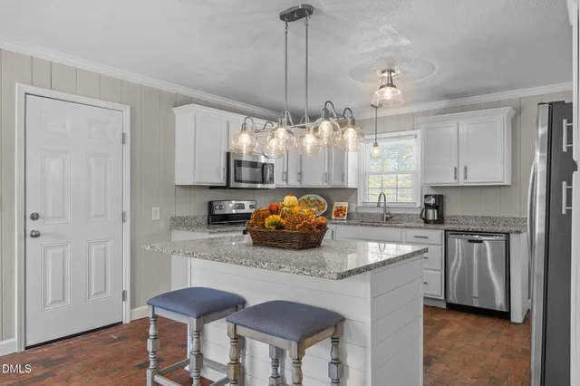 a kitchen with stainless steel appliances a dining table chairs and white cabinets