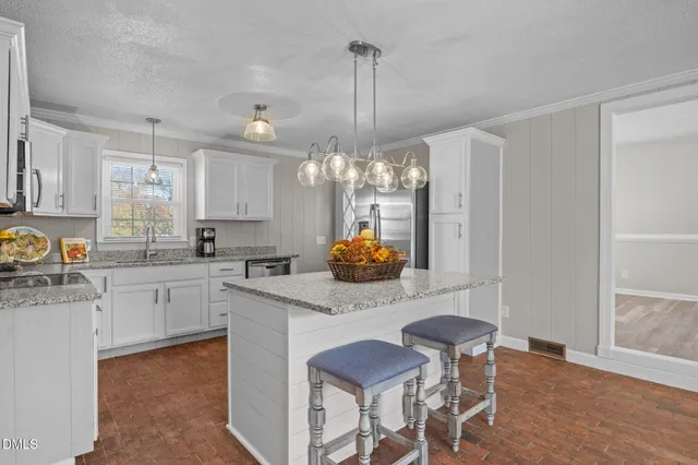 a living room with stainless steel appliances kitchen island granite countertop furniture and a refrigerator