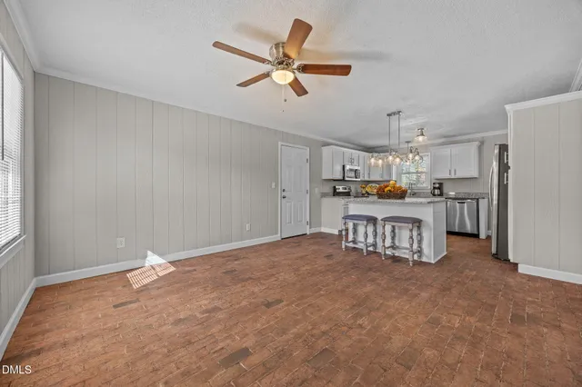 a living room with stainless steel appliances kitchen island granite countertop a refrigerator and a stove top oven