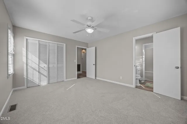 an empty room with windows and ceiling fan